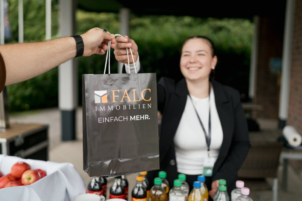 Content Fotograf, eine Dame, die einem Herren eine Tasche überreicht.