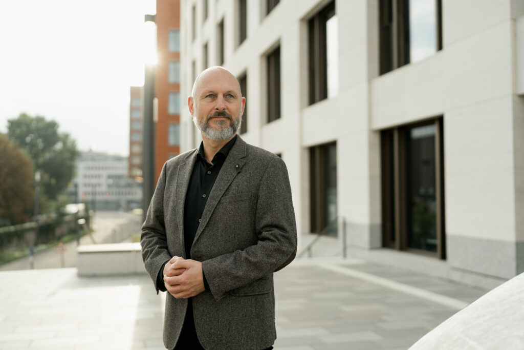Content Fotograf, ein Business Herr in einem grauen Jacket, der in die Ferne schaut.