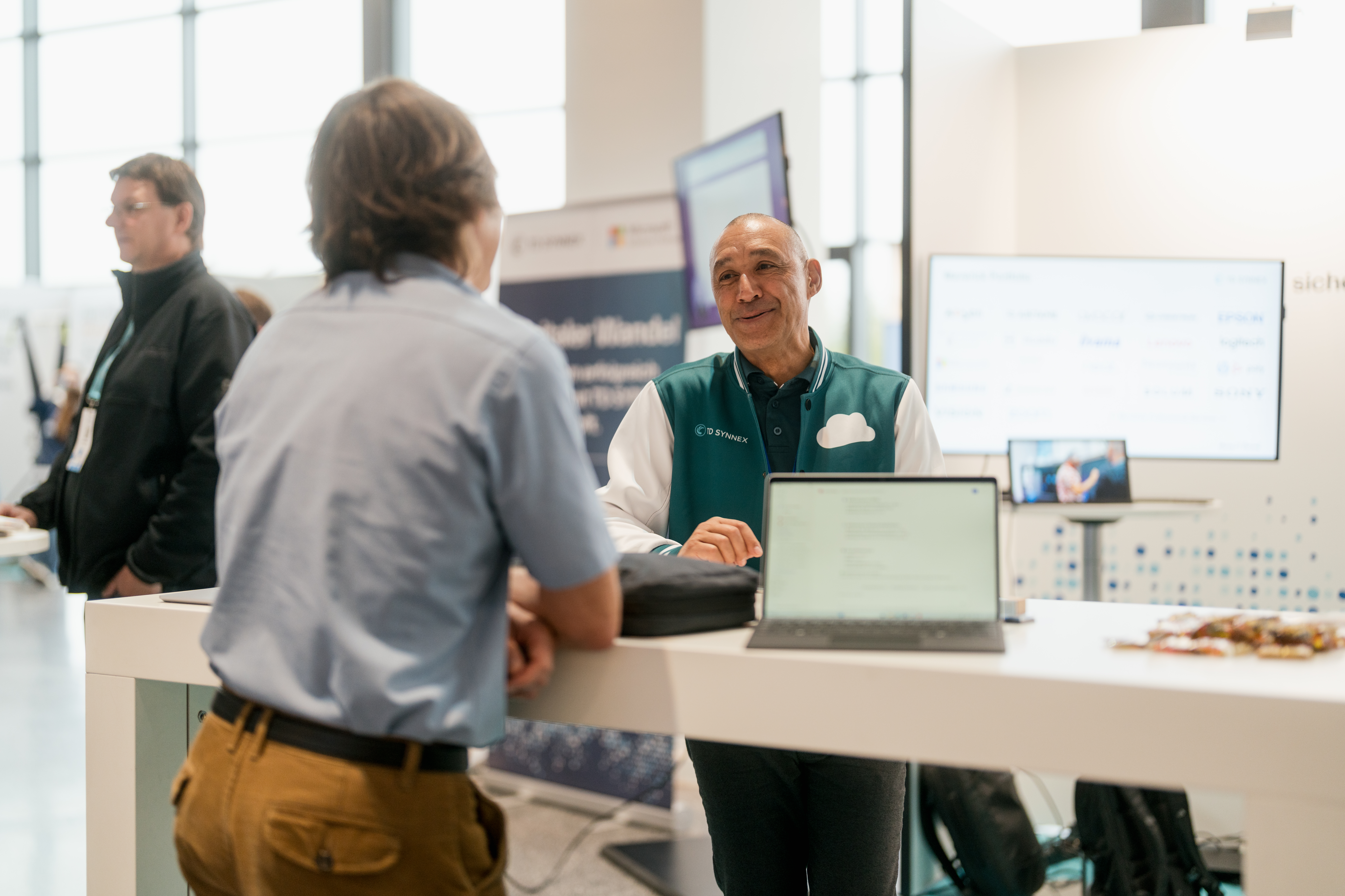 Content Fotograf, Zwei Herren auf einer Messe. Der eine Herr berät den anderen.