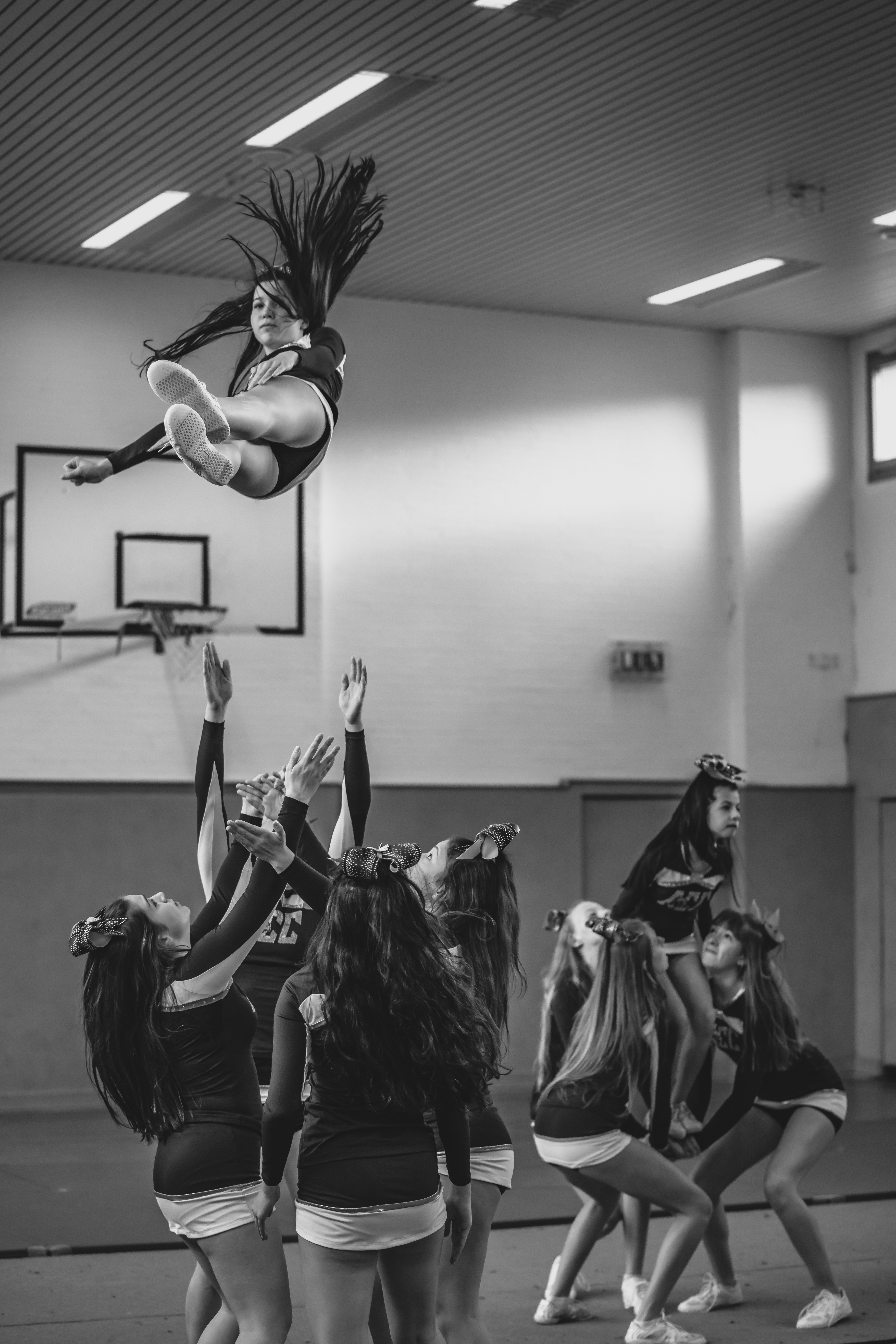 Cheerleader beim Training, die gerade ein Cheerleader in die Lüfte werfen