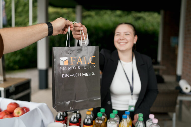 Content Fotograf, eine Dame, die einem Herren eine Tasche überreicht.