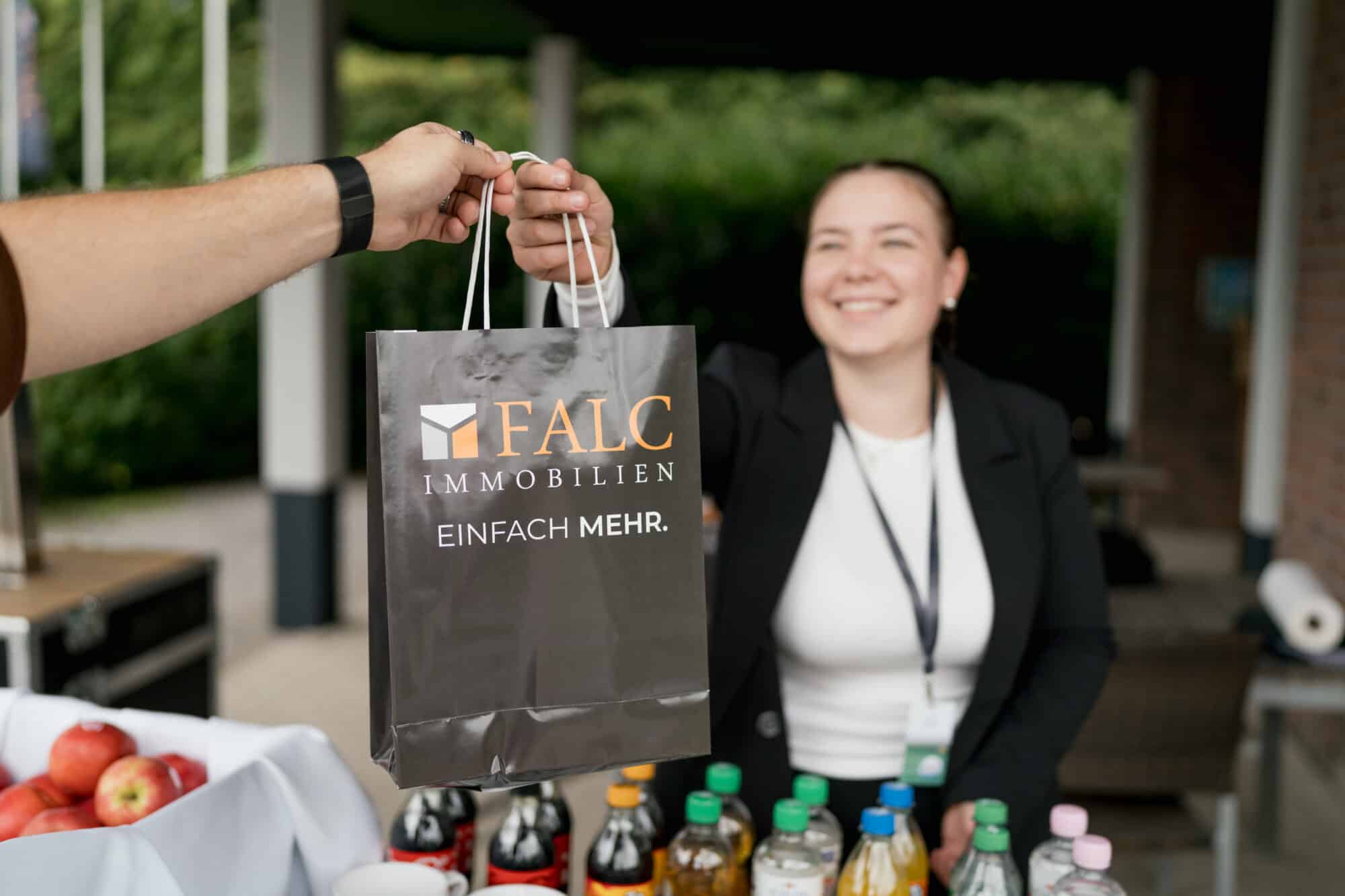 Content Fotograf, eine Dame, die einem Herren eine Tasche überreicht.