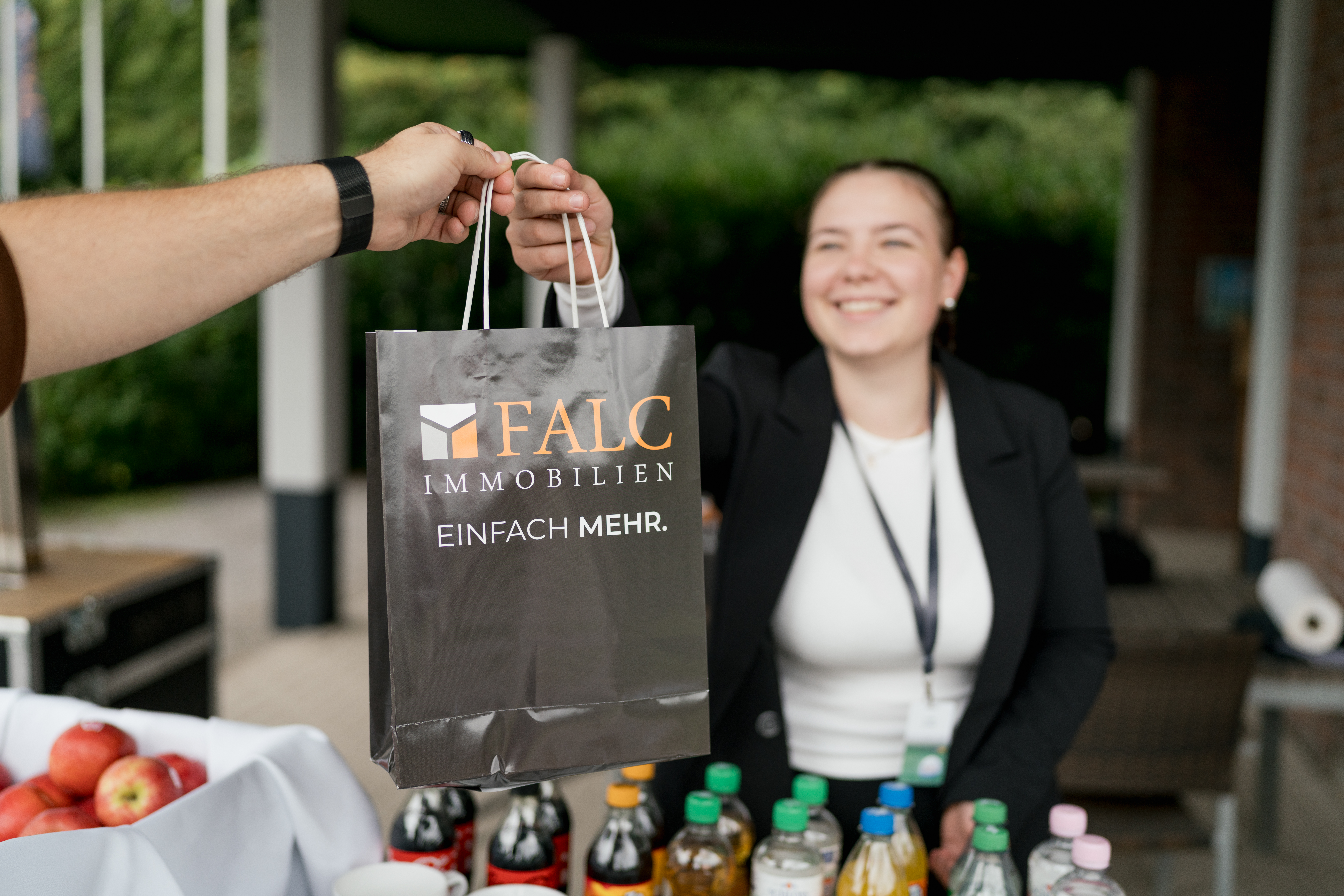 Content Fotograf, eine Dame, die einem Herren eine Tasche überreicht.