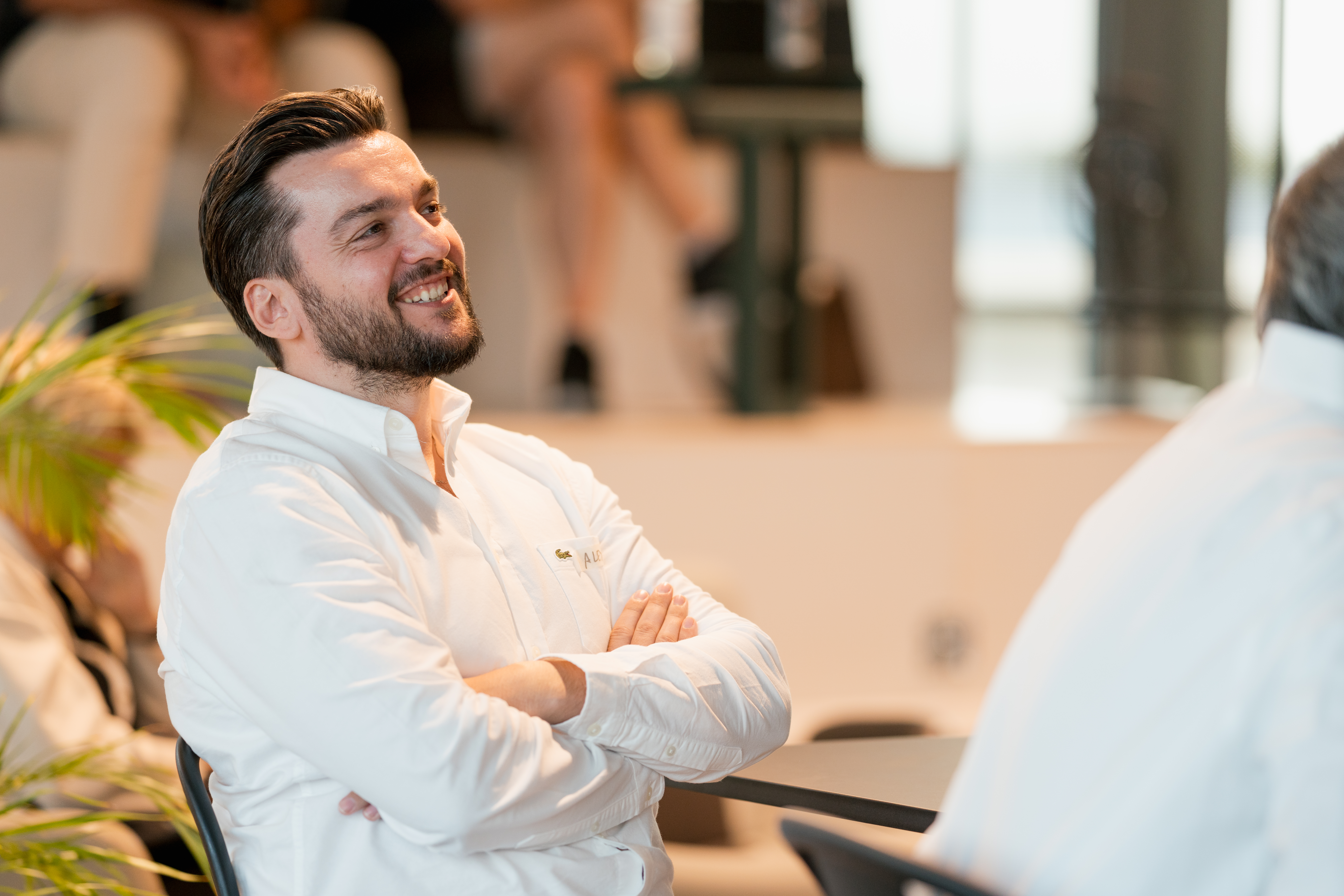 Lächelnder Mann sitzt entspannt bei einem Afterwork-Event