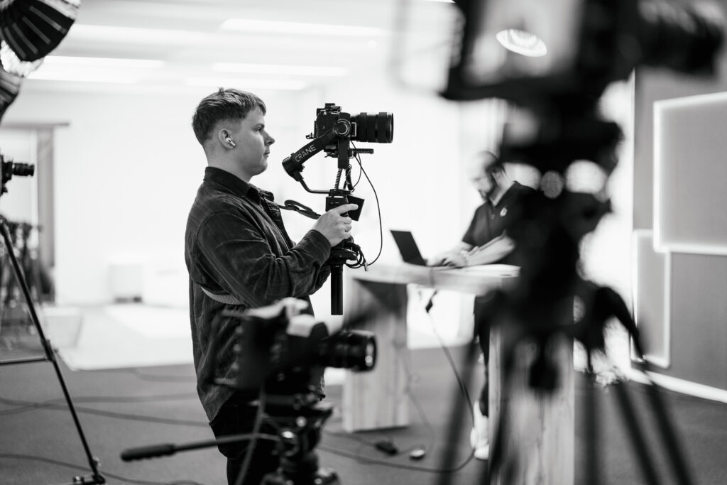 Content Fotograf, ein Mann mit einem Kamera Set up in der Hand, dieser filmt eine Szenerie.