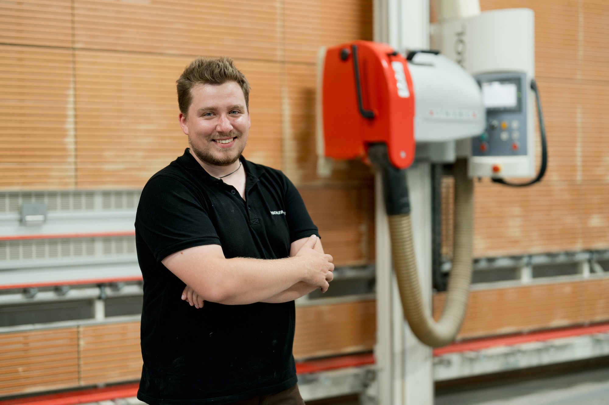 Kleidung beim Business-Fotoshooting: 5 Tipps für ein Ergebnis, das wirklich überzeugt 8 Unternehmensbild von einem Mann in einer Werkstatt. Er steht vor einer Maschine. - Kleidung Fotoshooting Business