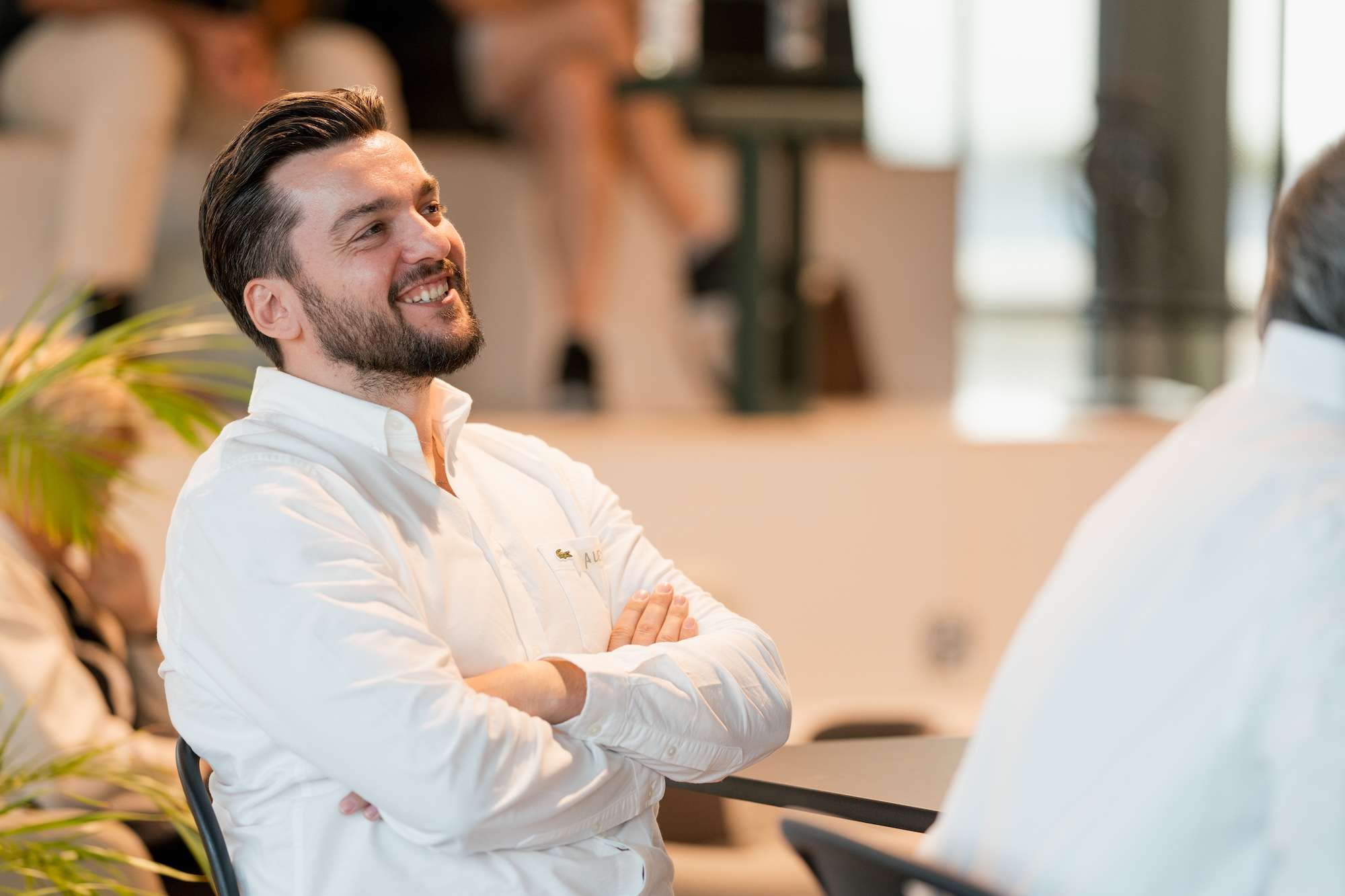 Lächelnder Mann sitzt entspannt bei einem Afterwork-Event