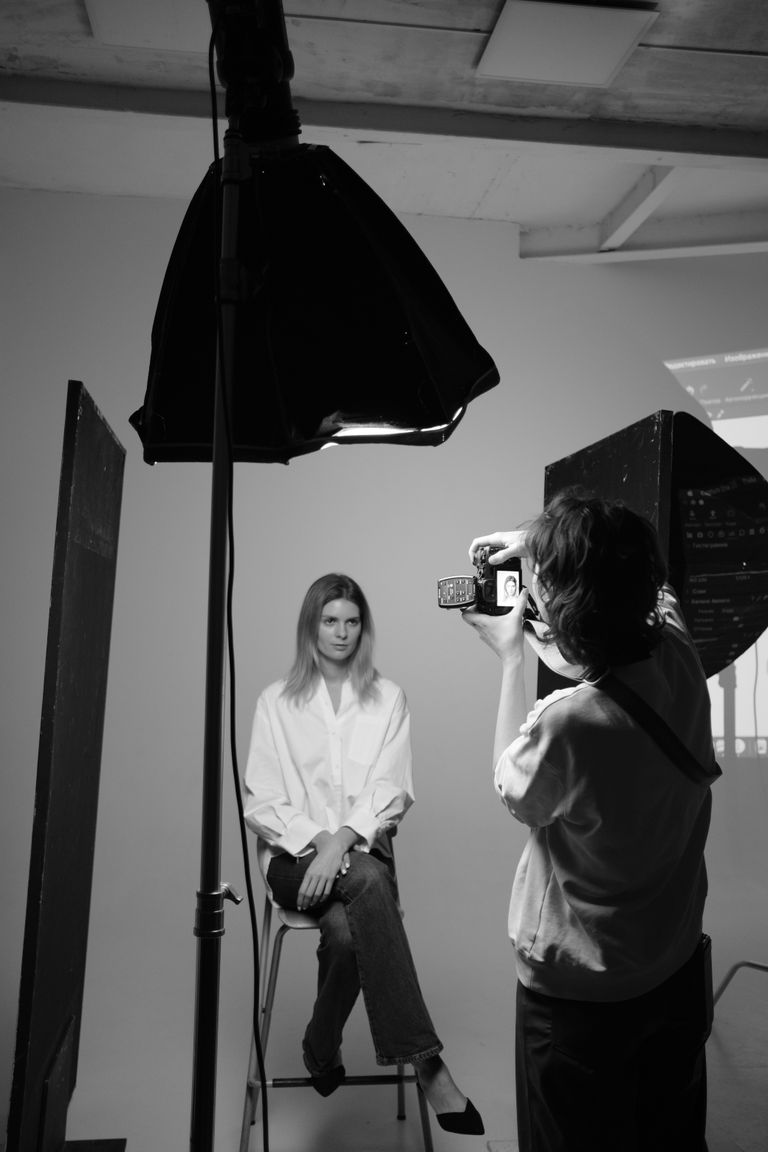 Elegant monochrome photo capturing a studio photoshoot with model and photographer.