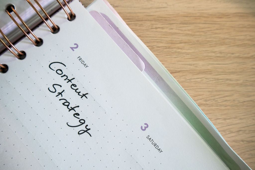 Fototermin Ablauf: Was Dich bei einem Business-Shooting wirklich erwartet 3 Top view of a notebook open to a day planner featuring 'Content Strategy' handwritten, lying on a wooden desk.